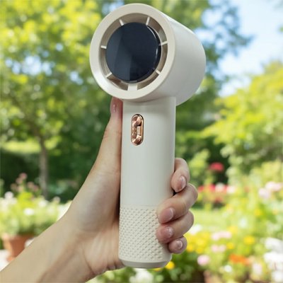 Mini ventilateur portable beige dans la main d'une femme 