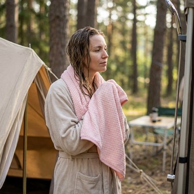 serviette de bain rose femme qui sort de la douche en camping