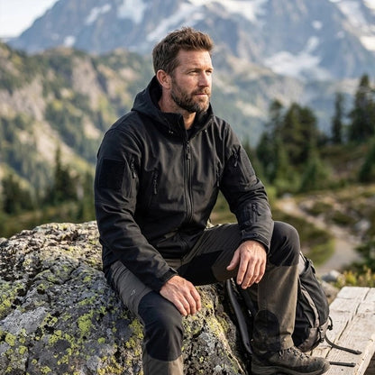 Veste randonnée homme​ noire homme assis sur une roche 